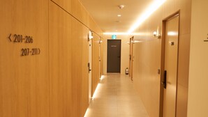 Un pasillo de hotel con paredes de madera y puertas numeradas, incluyendo una puerta para personal.