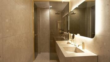 A modern bathroom with a large mirror, two sinks, and a shower area.
