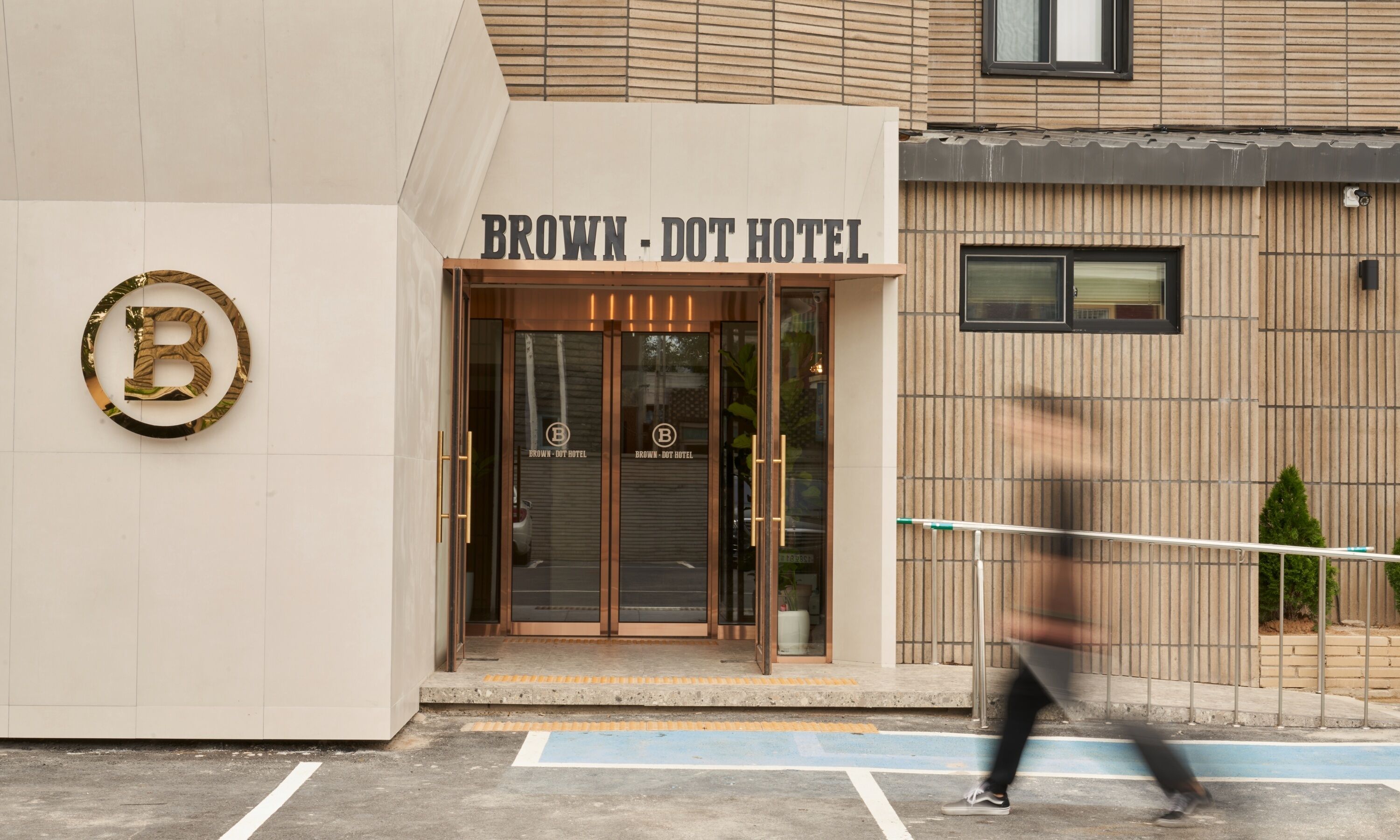 La entrada del Hotel Brown-Dot con un gran logo en forma de 'B' en la pared.