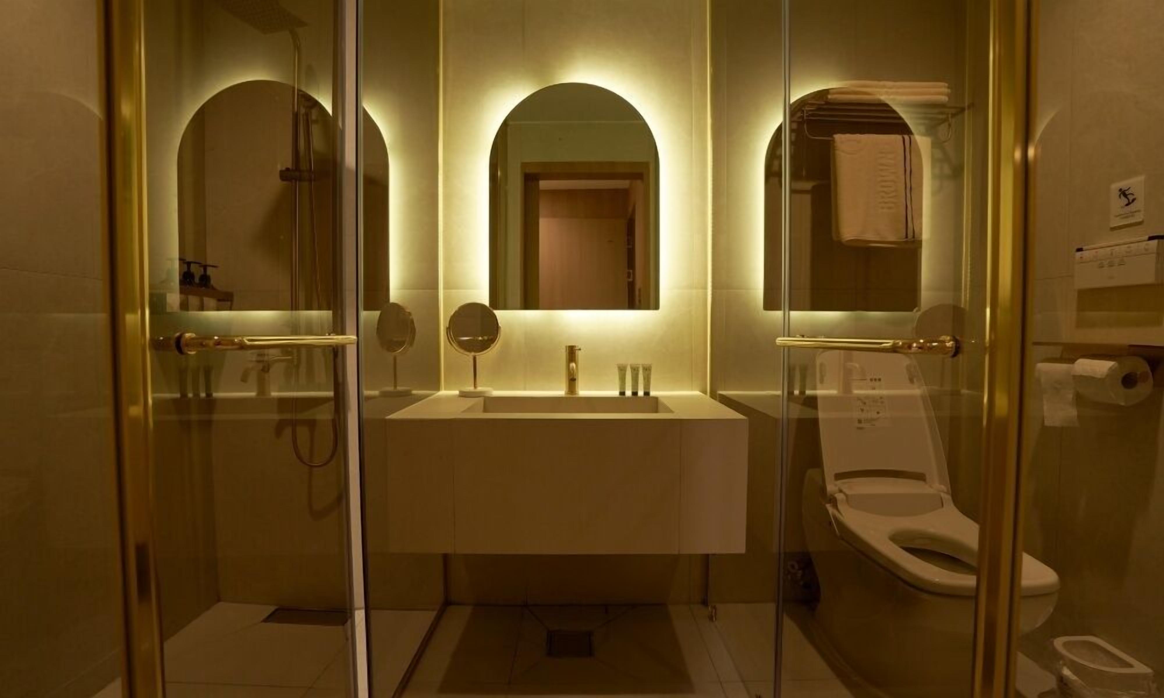 A bathroom with a glass-enclosed shower, a sink with a mirror, and a toilet.