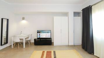 Habitación moderna y bien iluminada con un escritorio, una silla y un televisor mostrando un sitio web de bienes raíces.