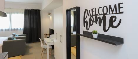 A modern living room with a sofa, a dining table, and a 'WELCOME home' sign on the wall.