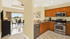 A modern kitchen with stainless steel appliances, wooden cabinets, and a dining area with a view.