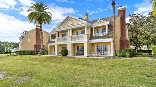 A large, two-story house with a spacious front yard, a balcony, and a chimney.