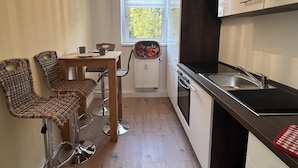 Eine kompakte Küche mit Essbereich, inklusive Tisch und Stühlen, einem Fenster mit Aussicht und modernen Geräten.