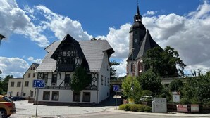 Ein traditionelles Fachwerkhäus mit einem Kirchturm, einer Kopfsteinpflasterstraße und einem Kreisverkehr.