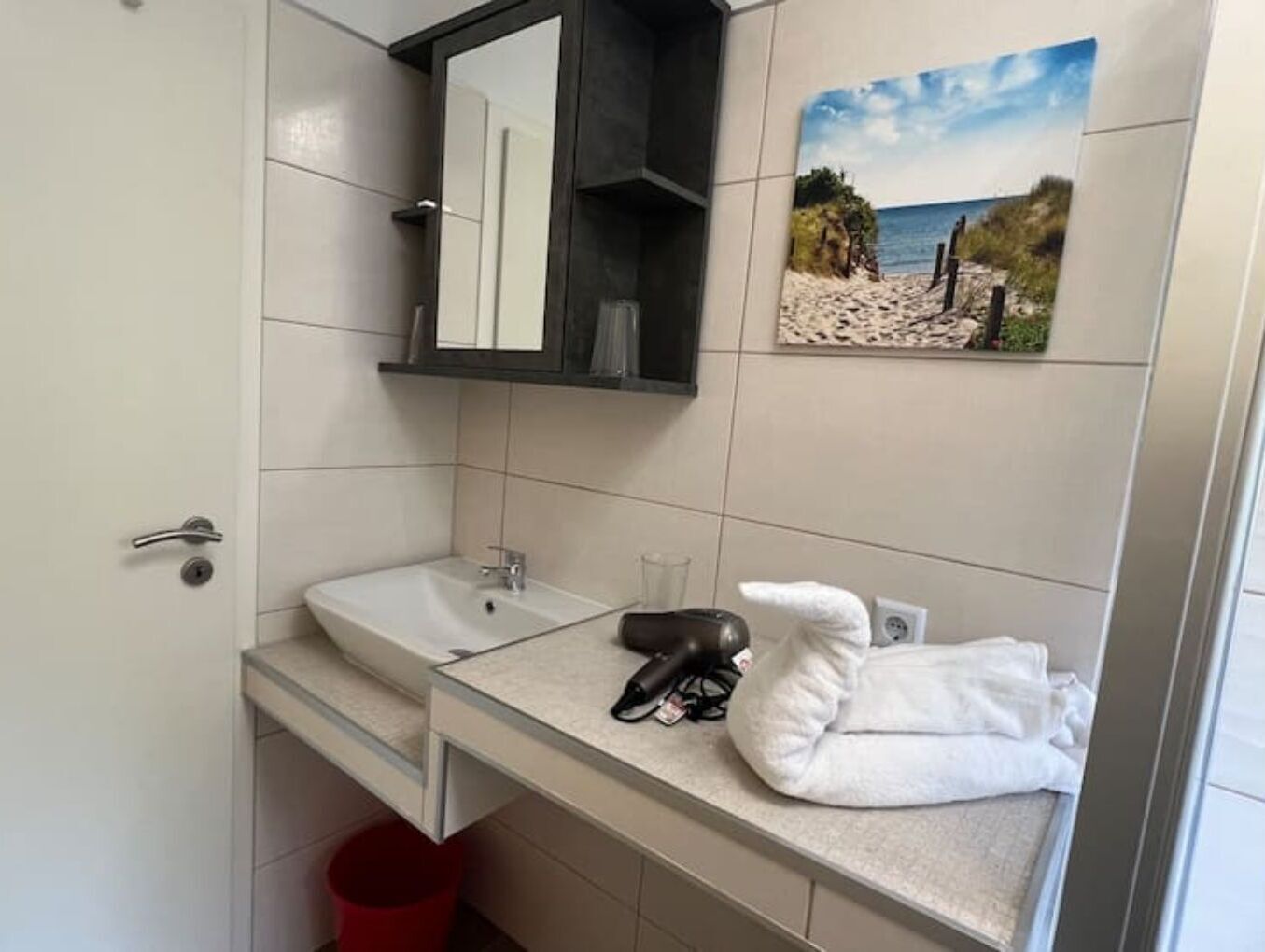 Een badkamer met een witte wastafel, een spiegel en een handdoekhouder.