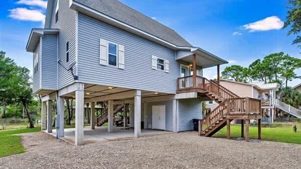 A two-story house with a covered patio and a wooden deck. - Tagged Out Canal Front, Dock 3 bedroom 2 bath (St. George Island)