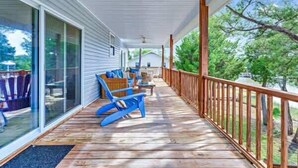 A covered porch with a wooden deck, blue chairs, and a glass door leading to a patio area. - Tagged Out Canal Front, Dock 3 bedroom 2 bath (St. George Island)