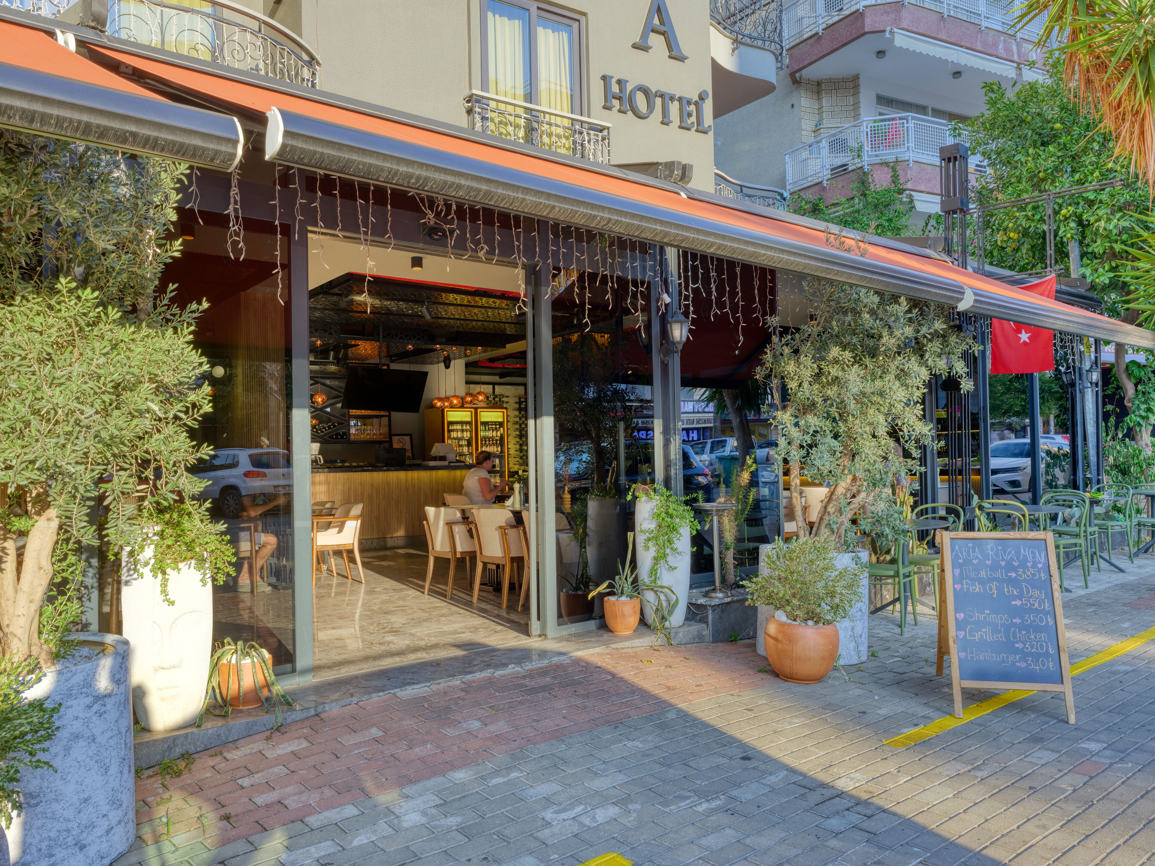 A hotel with outdoor seating, a bar, and a signboard with menu items.