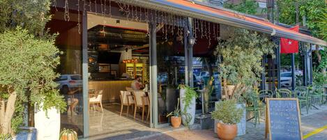 A hotel with outdoor seating, a bar, and a signboard with menu items.