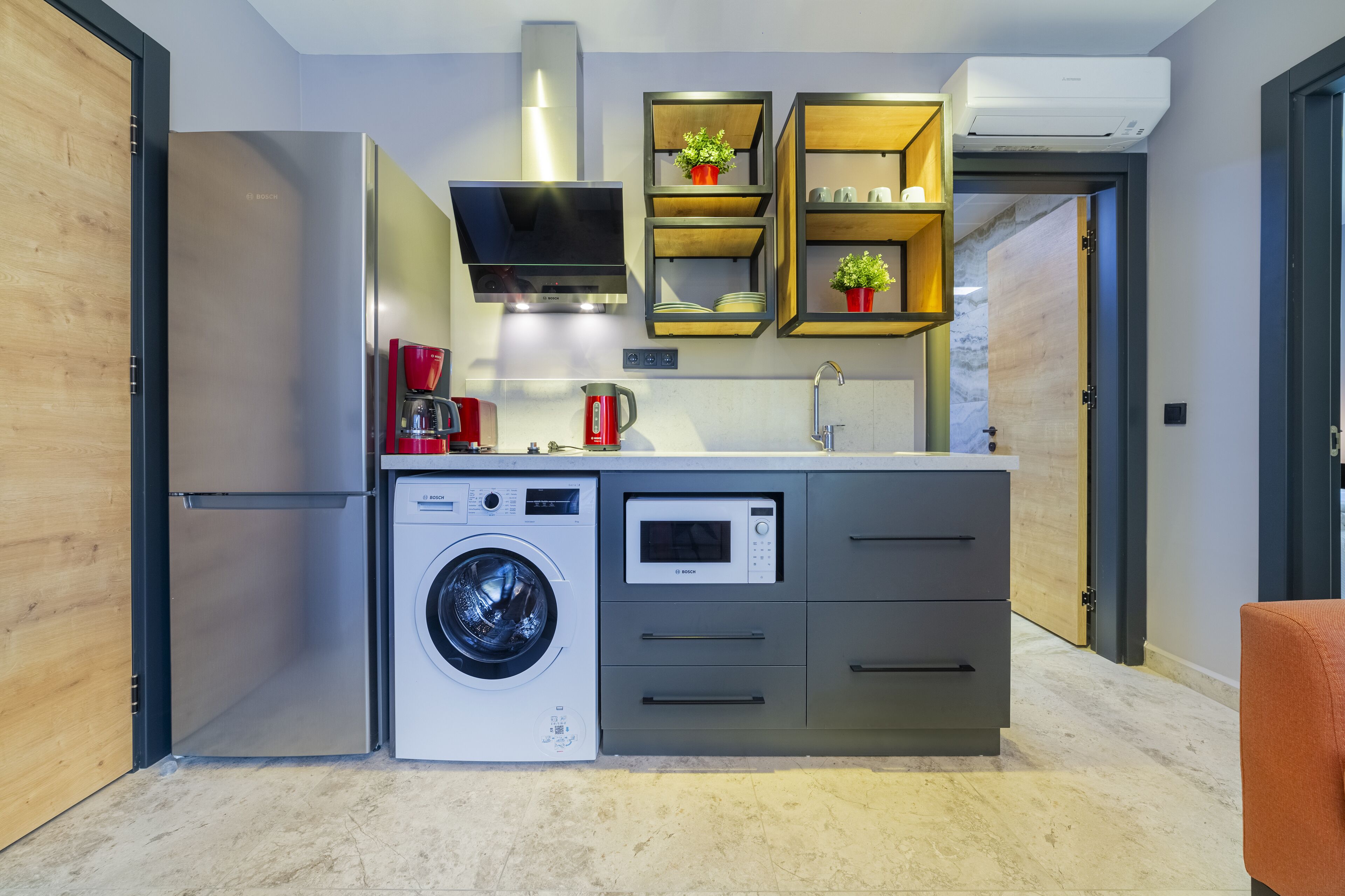 A compact kitchen with a washing machine, microwave, and coffee maker.