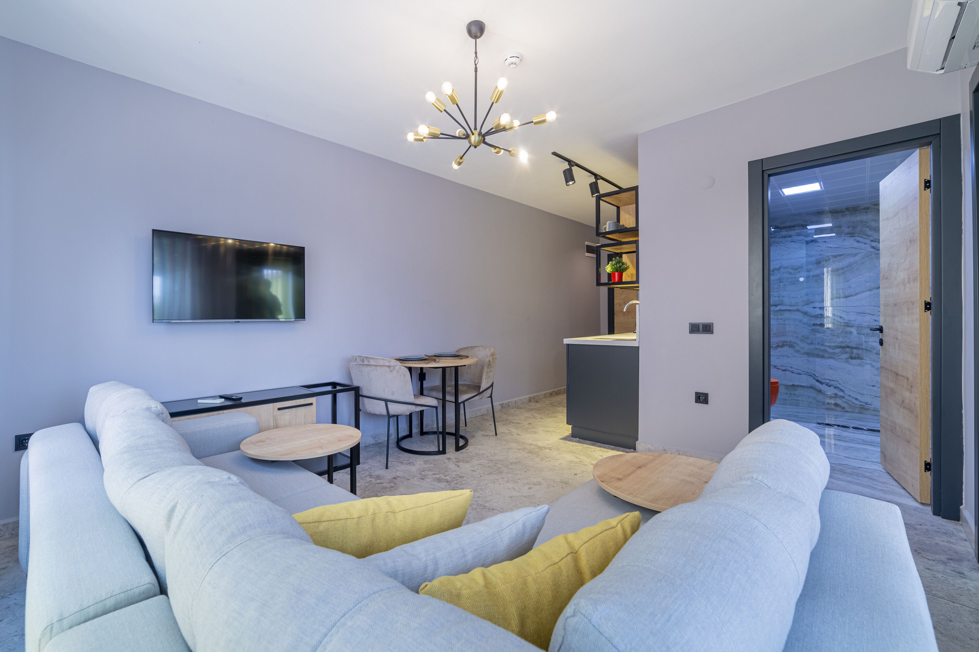 A modern living room with a sofa, a dining table, and a TV.