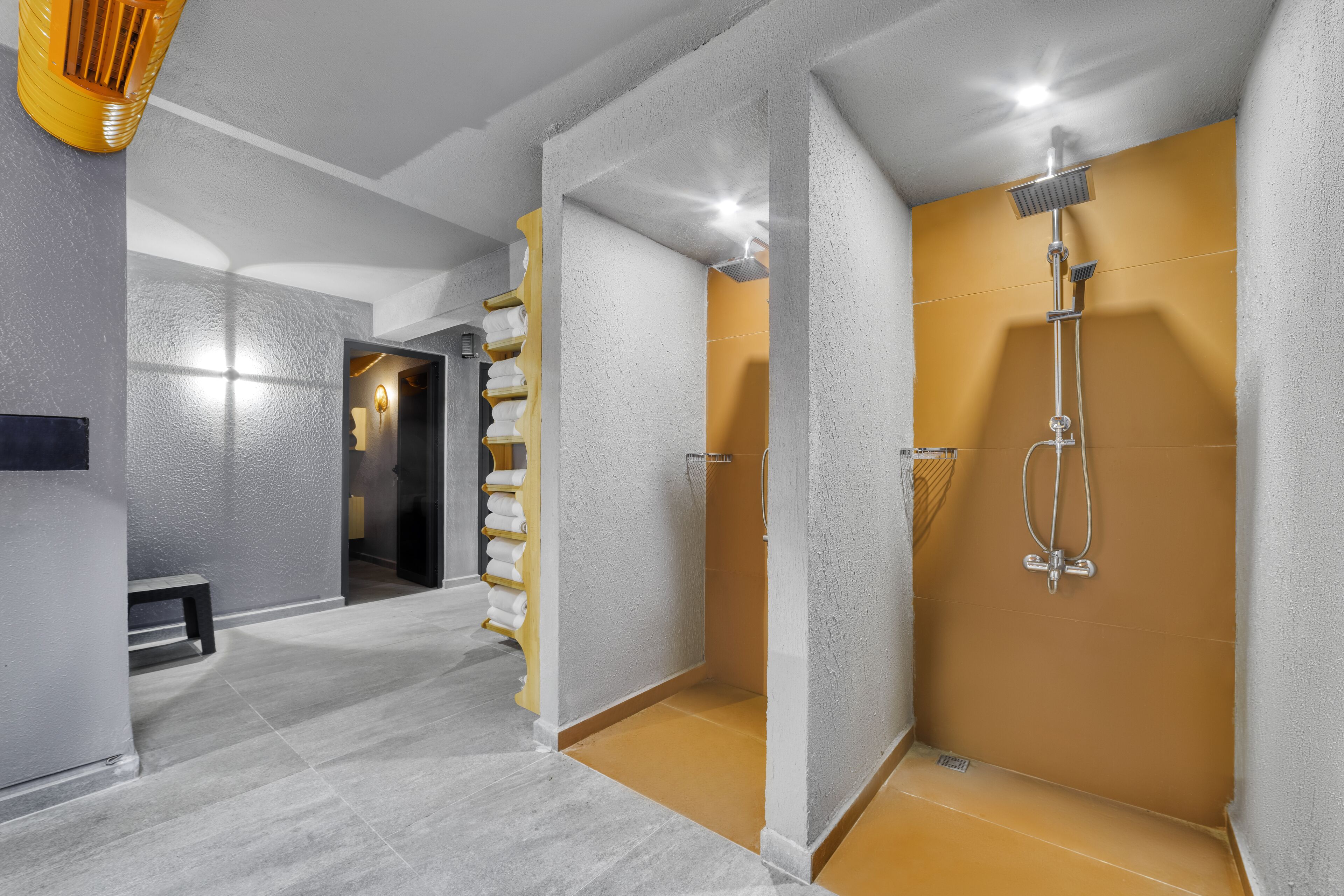 A modern bathroom with a shower, a bench, and a towel rack.