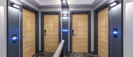 Un ascenseur au design moderne, doté d’un sol en marbre et de portes en bois.