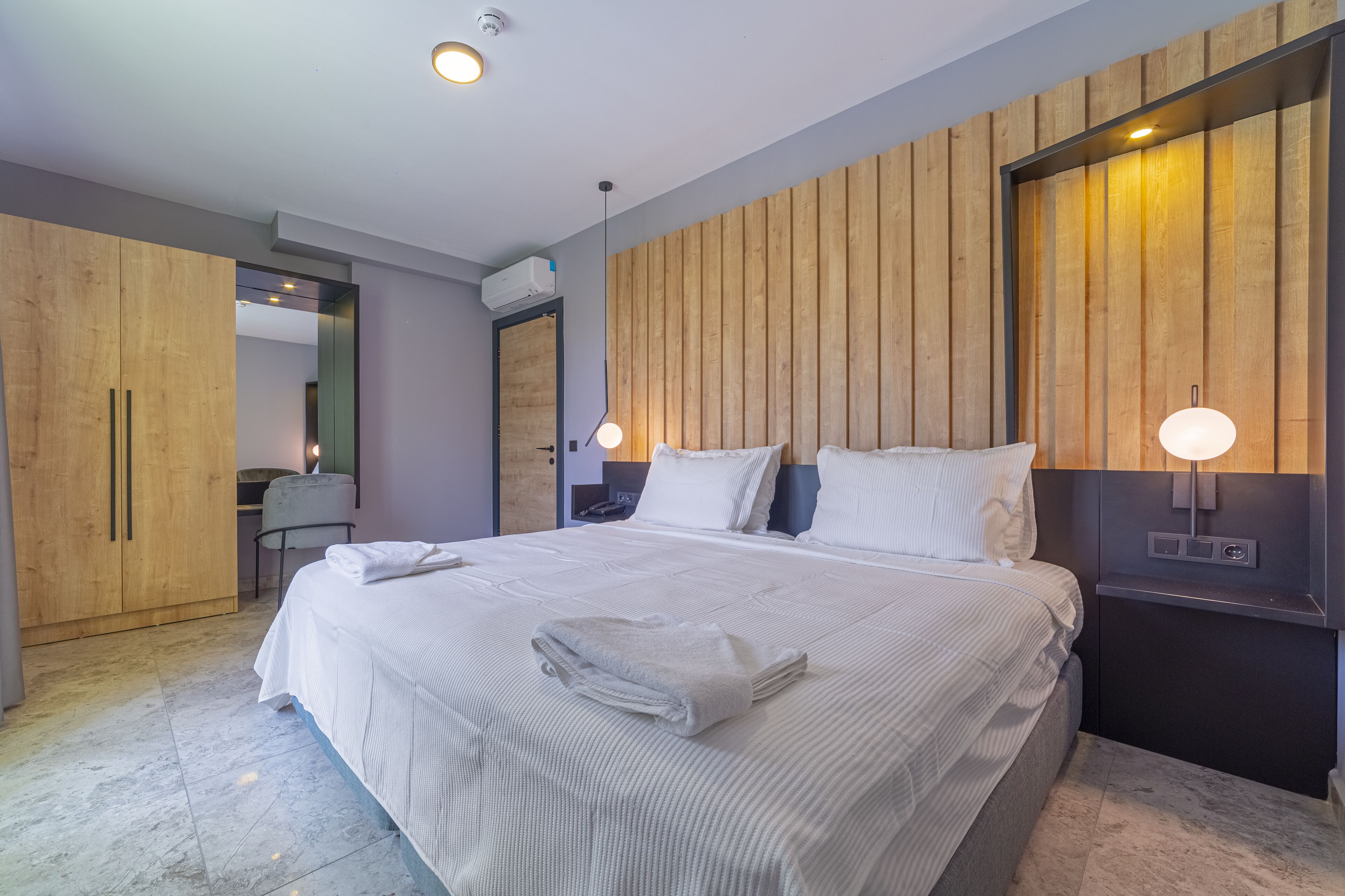 Una habitación de hotel moderna con una cama grande, un panel de pared de madera y un escritorio con una silla.