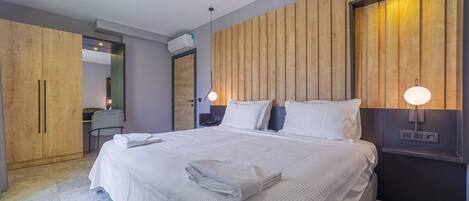 Una habitación de hotel moderna con una cama grande, un panel de pared de madera y un escritorio con una silla.