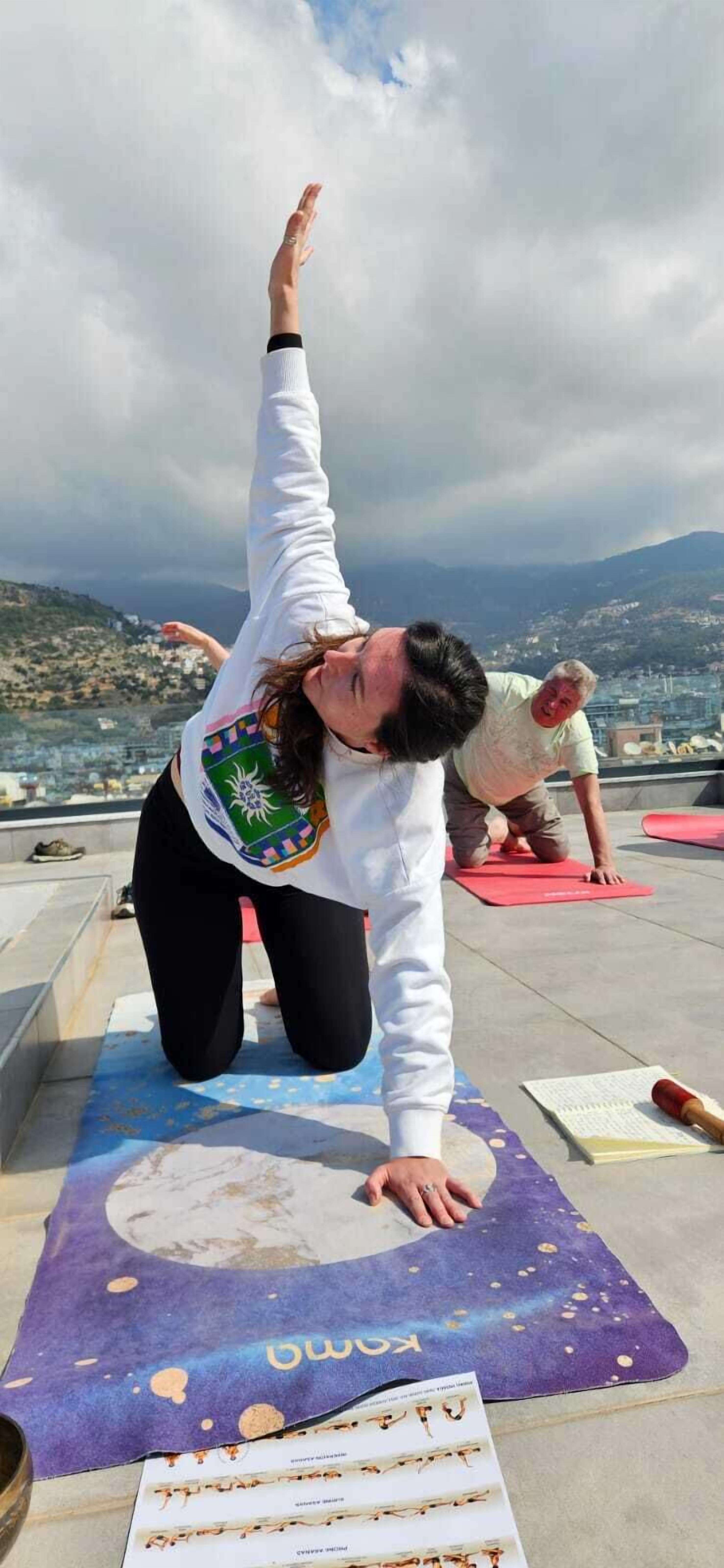 A person performing a yoga pose on a mat with a scenic view in the background.
