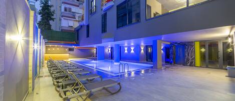 Zona de piscina de hotel con tumbonas y una piscina.