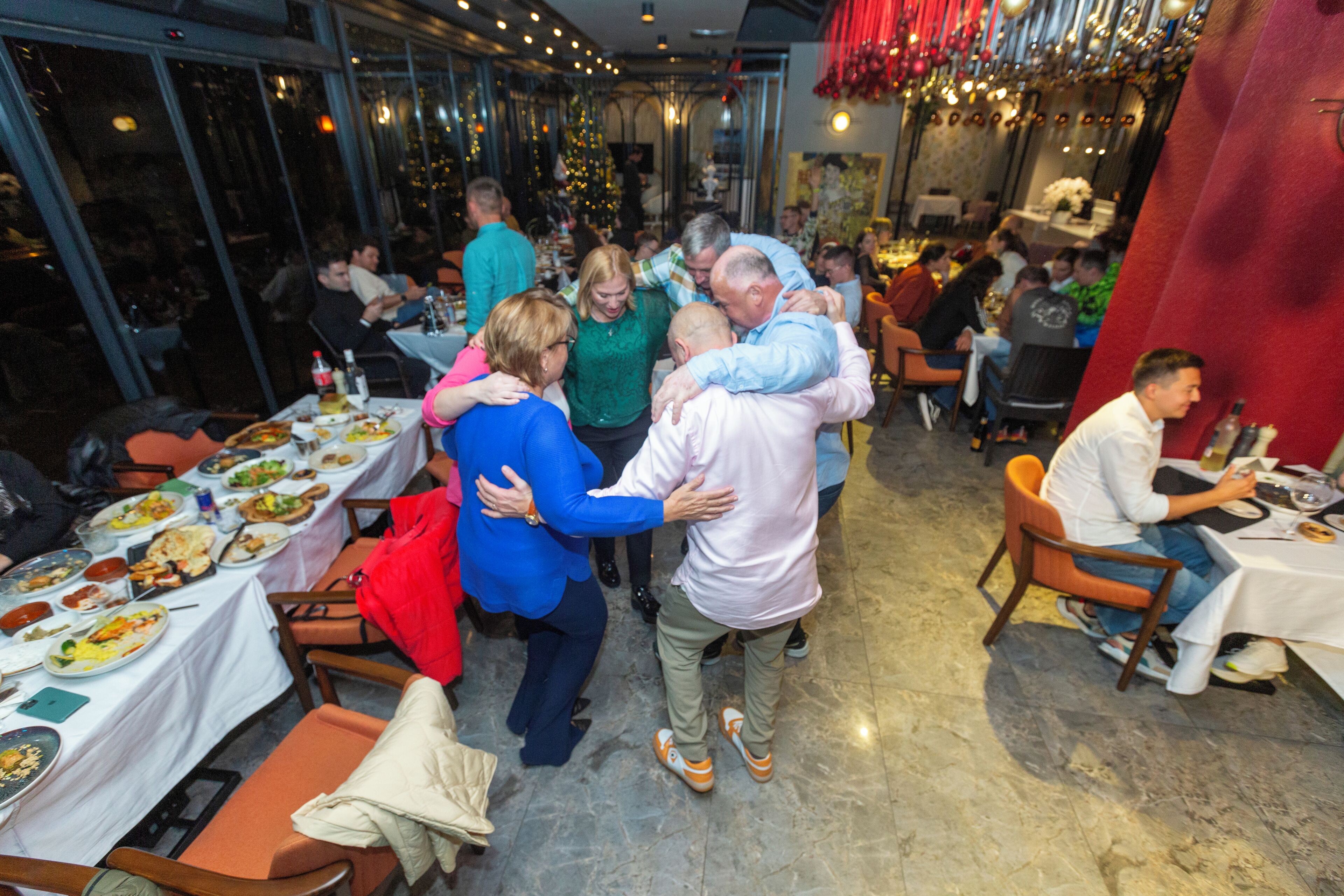 A restaurant with multiple tables and chairs, large windows, and a festive atmosphere.