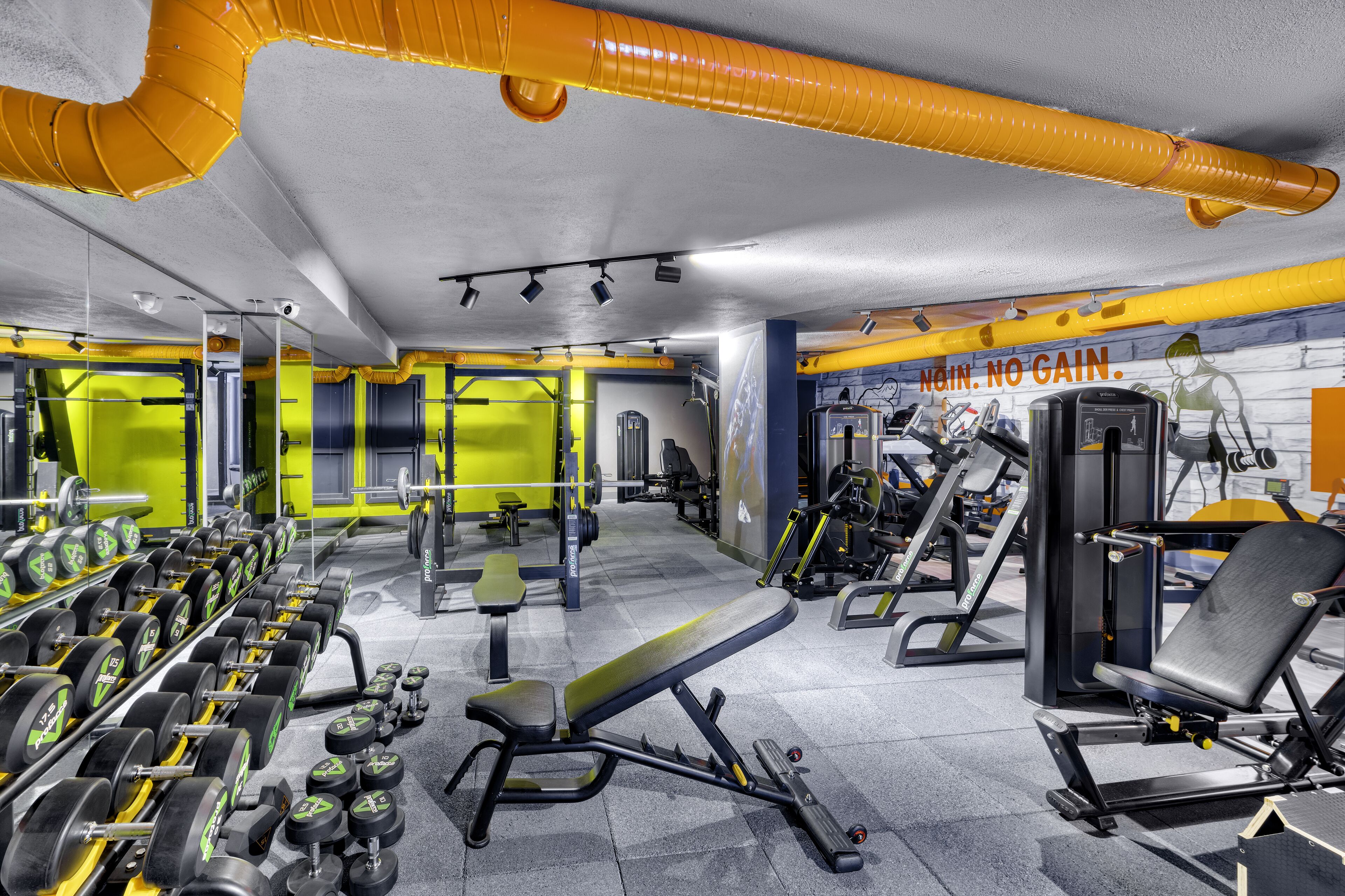 A gym with weightlifting equipment, benches, and exercise machines.