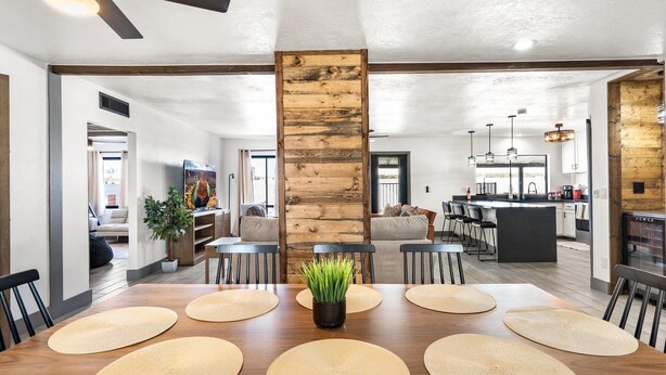 A spacious living area with a wooden accent wall, a dining table with woven placemats, and a kitchen in the background. - Home in the Heart of Glendale (Glendale)
