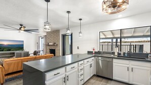 A modern kitchen with white cabinets, a large island, and pendant lighting. - Home in the Heart of Glendale (Glendale)