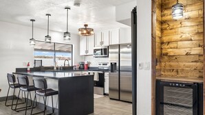 A modern kitchen with a central island, stainless steel appliances, and a wooden accent wall. - Home in the Heart of Glendale (Glendale)