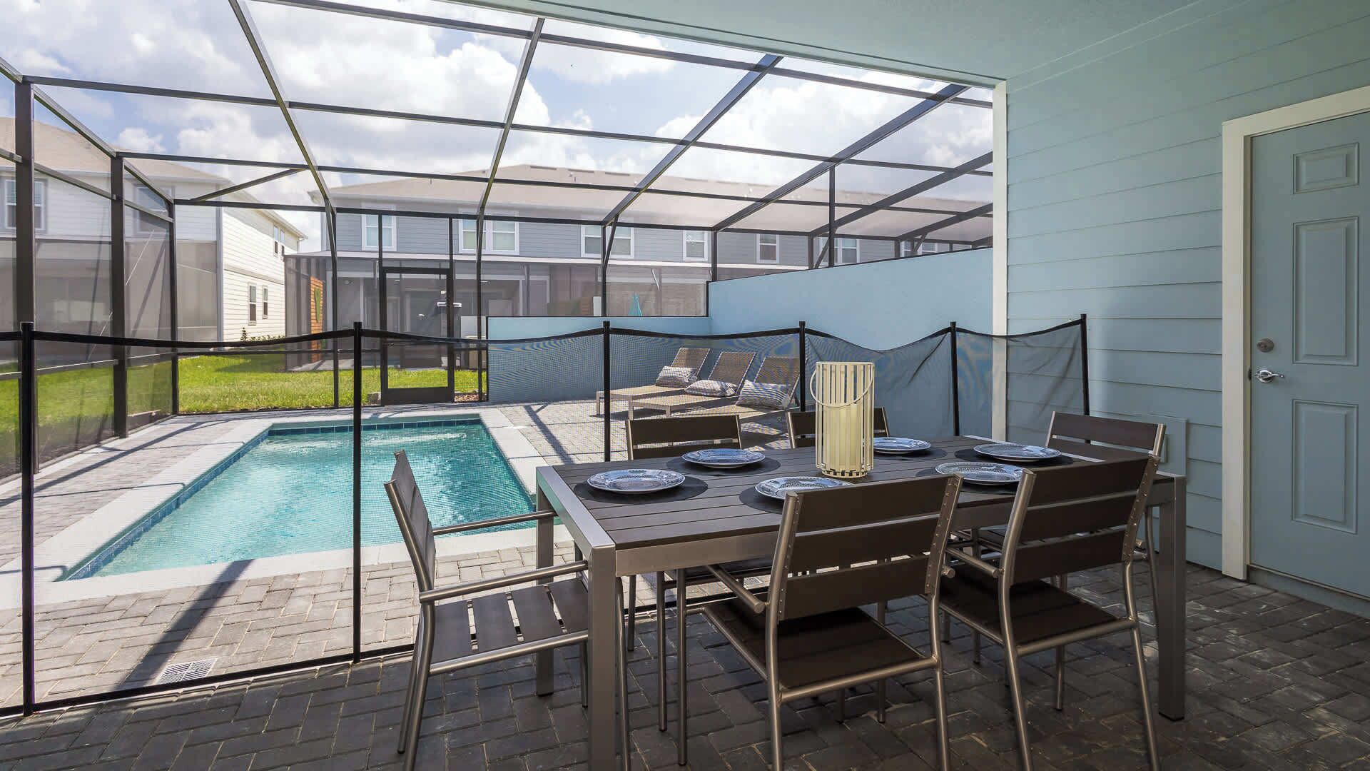 A covered patio with a pool, outdoor seating, and a table set for dining.