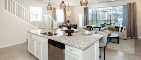 A spacious kitchen with granite countertops, a dishwasher, and a dining area with a round table and chairs.