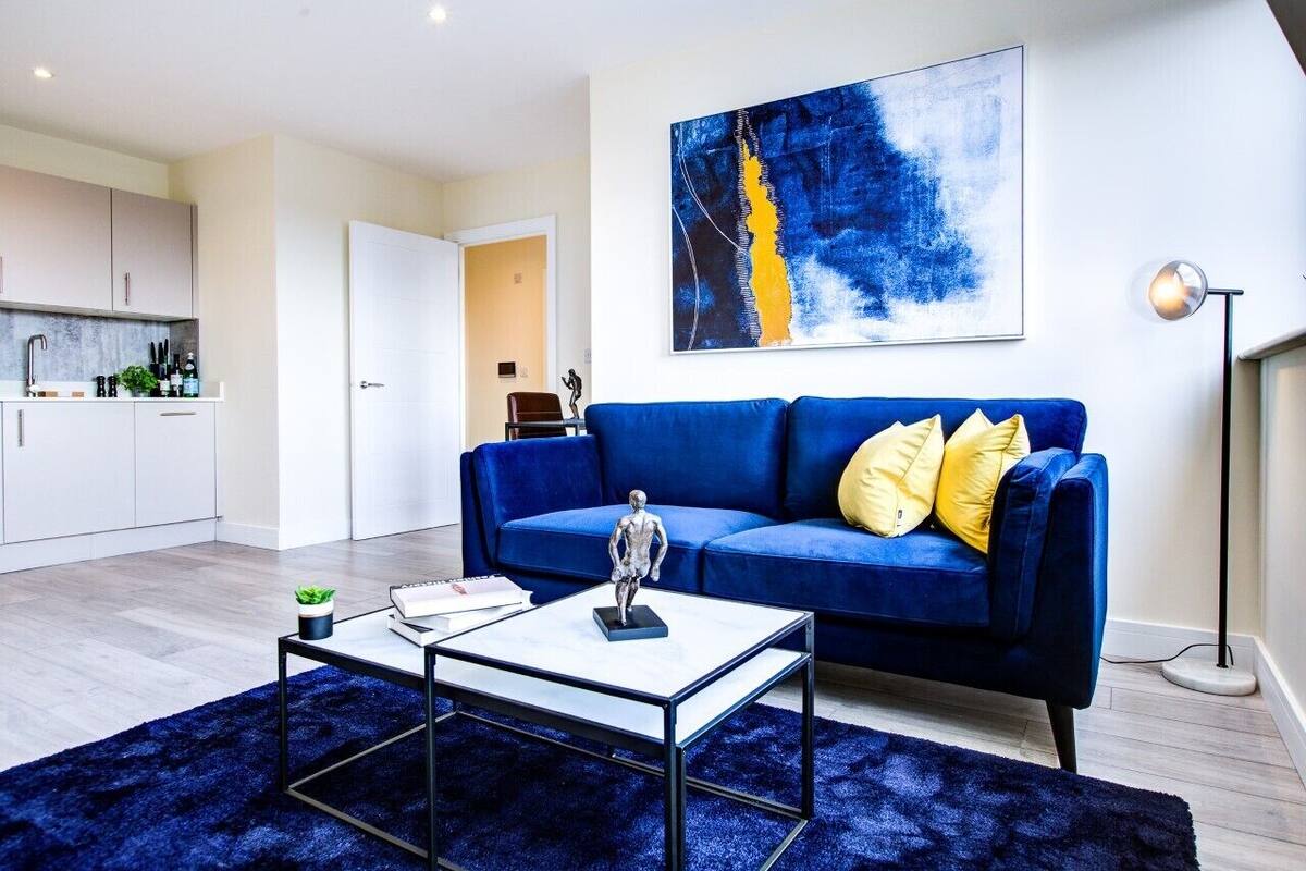A modern living room with a blue sofa, a coffee table, and a painting on the wall.