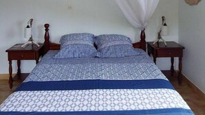 Una cama con una colcha estampada, dos mesitas de noche con lámparas y un mosquitero sobre la cama.