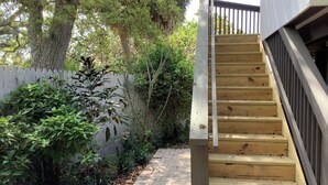 Una escalera de madera que lleva a un balcón con baranda blanca.