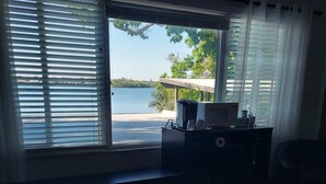 Una habitación con cama, un escritorio con computadora y una ventana con persianas.