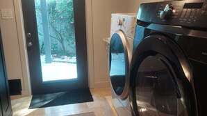 Un cuarto de lavandería con lavadora, secadora y puerta al exterior.
