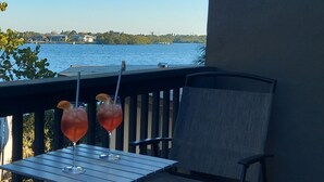 Una terraza con dos bebidas sobre una mesa, con vista a un cuerpo de agua.
