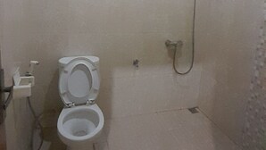 A small, tiled bathroom with a toilet, a shower, and a small window. - Hotel O Modena Homestay Syariah Near SD Negeri 101798 Deli Tua (Medan)
