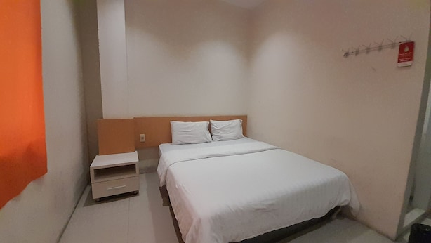 A small, neatly arranged bedroom with a single bed, a nightstand, and a wall-mounted shelf. - Hotel O Modena Homestay Syariah Near SD Negeri 101798 Deli Tua (Medan)