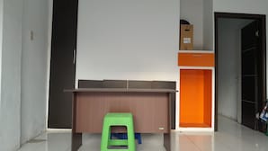 A room with a wooden desk, a green stool, and an orange cabinet. - Hotel O Modena Homestay Syariah Near SD Negeri 101798 Deli Tua (Medan)