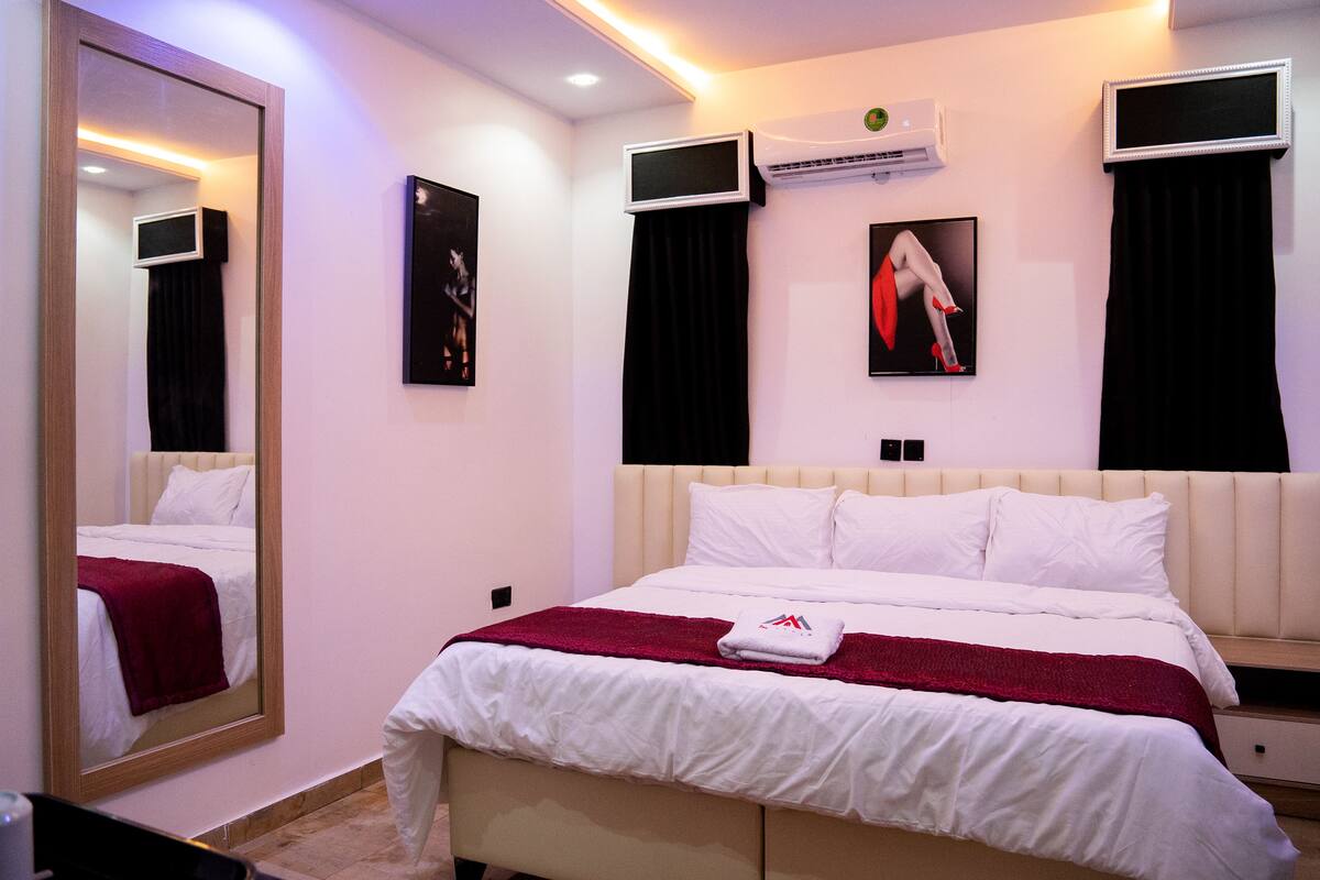 Een moderne hotelkamer met een groot bed, een spiegel, een televisie en een airconditioning.