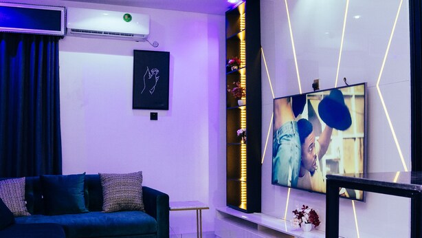 Uma sala de estar moderna com sofá, mesa de centro e televisão na parede.