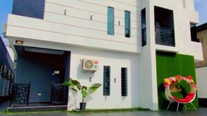 Um edifício moderno de dois andares com telhado plano, janelas amplas e uma porta verde.