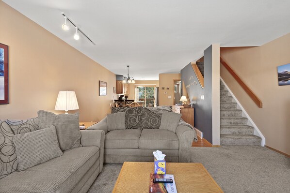 A living room with a sectional sofa, a coffee table, and a staircase.