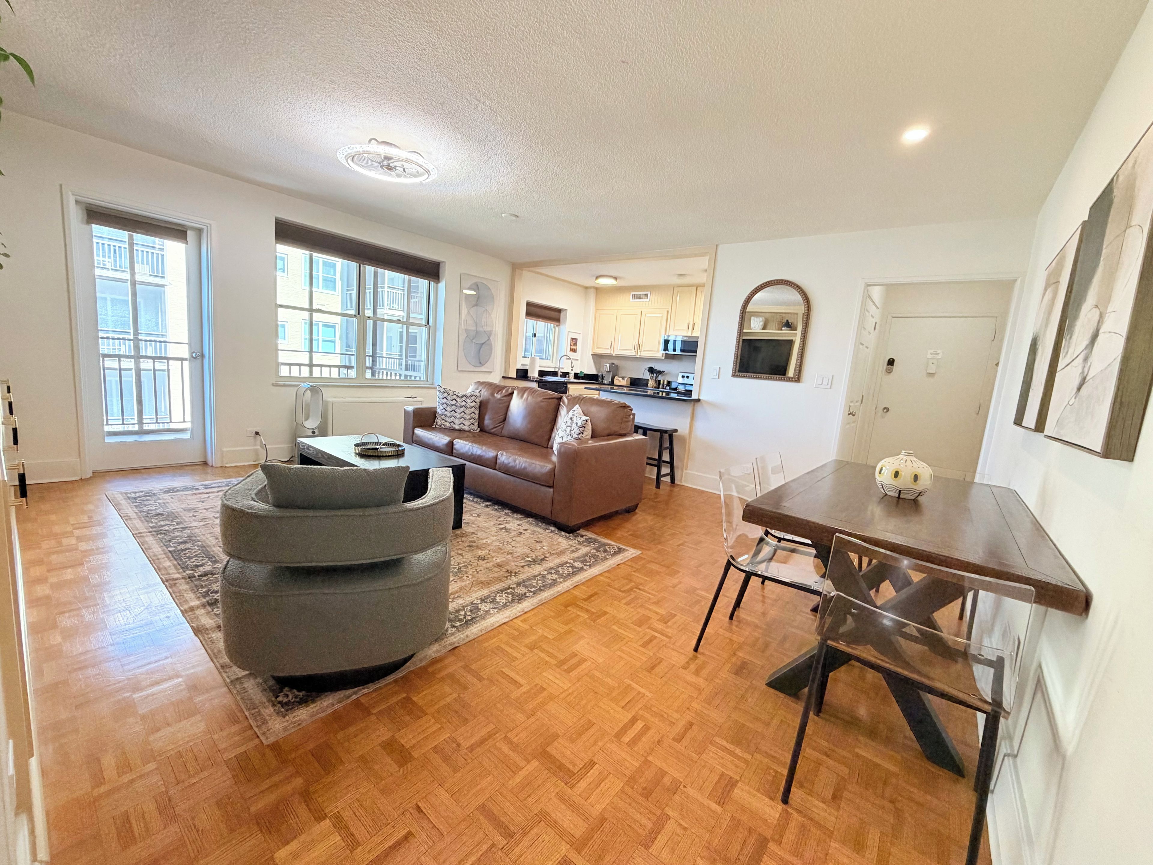 A spacious living area with a sofa, ottoman, and dining table.
