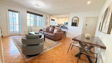 A spacious living area with a sofa, ottoman, and dining table.