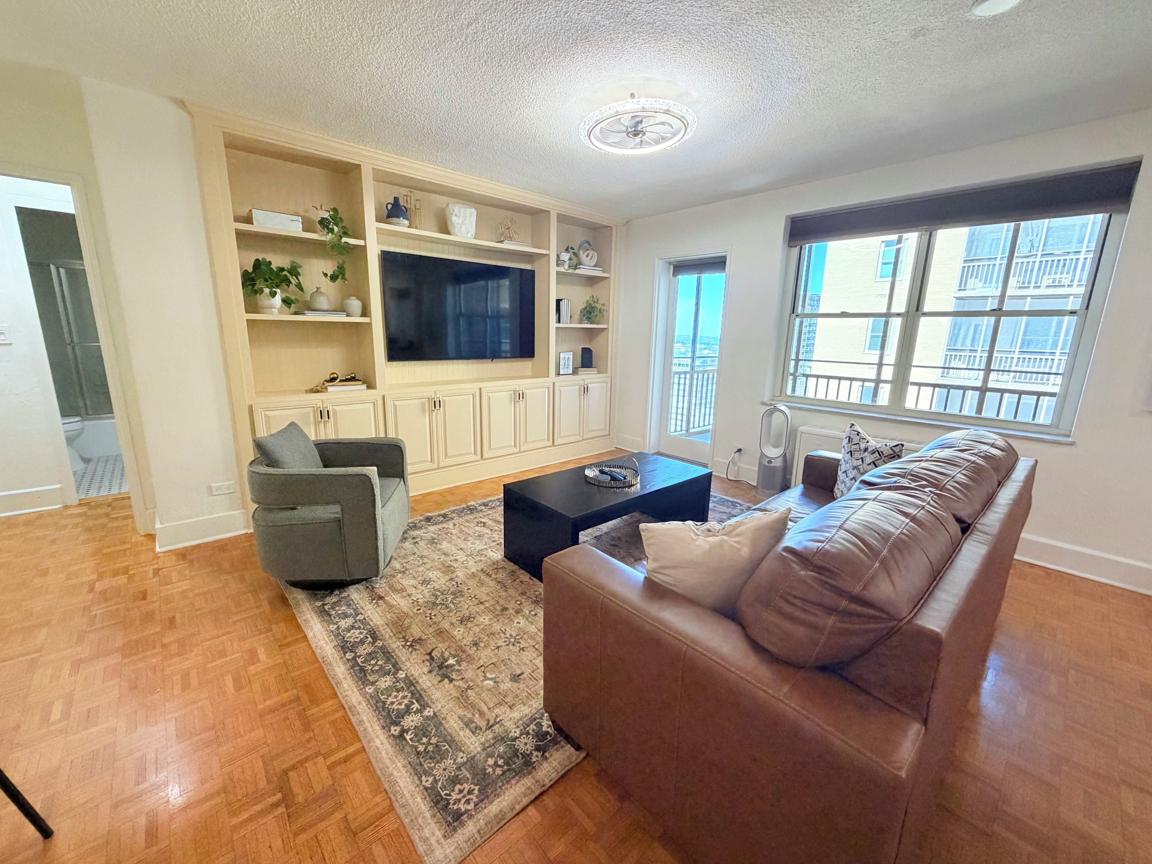 A living room with a sofa, a coffee table, a TV, and built-in shelving.