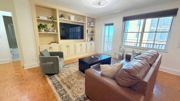 A living room with a sofa, a coffee table, a TV, and built-in shelving.