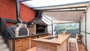 An outdoor kitchen area with a brick oven, a sink, and a wooden bar counter.