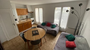 A compact living space with a kitchenette, a dining area, and a sofa with cushions.