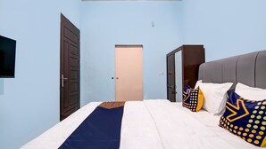 A bedroom with a bed, a wardrobe, a television, and a door.